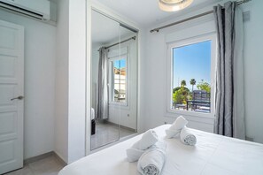 Ein Hotelzimmer mit einem Bett, einem großen Fenster, einem Spiegel und einer Tür.