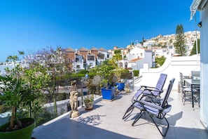A rooftop patio with outdoor furniture, potted plants, and a view of a hillside town. - Tropicana 6C by Casasol (Nerja)