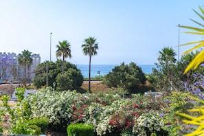 A coastal landscape with a view of the sea, palm trees, and a variety of flowering plants. - Tropicana 6C by Casasol (Nerja)