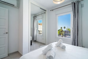 A hotel room with a bed, a large window, a mirror, and a door. - Tropicana 6C by Casasol (Nerja)