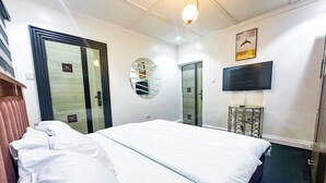 Ein Hotelzimmer mit einem Bett, einem Fernseher, einem Spiegel und einer Tür.