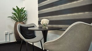 Ein modernes Interieur mit einem runden Tisch, zwei Stühlen, einem Topfpflanzen und einer dekorativen Vase mit Blumen.