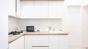 Una cocina moderna con armarios blancos, encimera de madera, microondas, estufa y fregadero.
