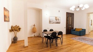 Una habitación con una mesa de comedor, sillas, un sofá, un tapete y un cuadro en la pared.
