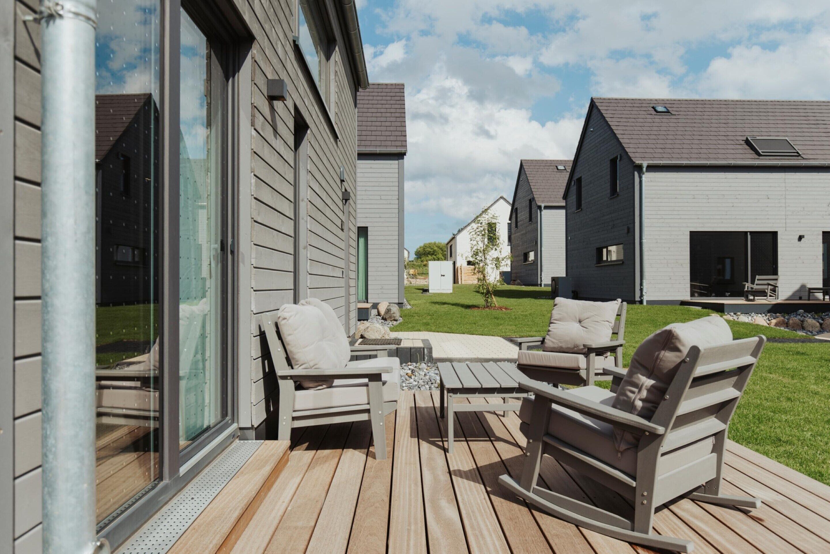An outdoor deck with wooden flooring, a glass door, and two rocking chairs.