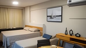 Hotellihuone, jossa on sänky, työpöytä, tuoli, pöytä ja ilmastointilaite.