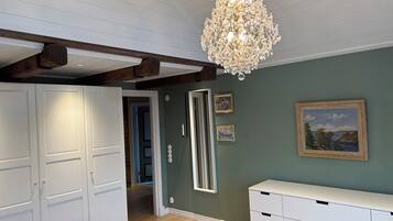Een kamer met een kroonluchter, een witte garderobe, een spiegel en een schilderij aan de muur.