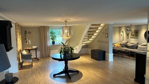 A modern living room with a dining area, a staircase, and a large window with a plant. - Large farmhouse near lake & forest • Boat included (Svängsta)