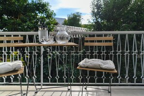 Un balcón con una mesa, sillas, una jarra y un jarro de vidrio.