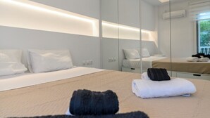 Ein modernes Hotelzimmer mit einem großen Bett, einem Nachttisch, einem Spiegel und einem Fenster mit Blick auf Grünflächen.