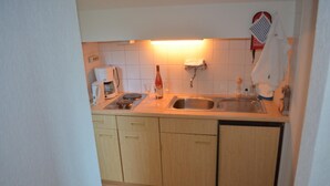 A compact kitchen with a sink, countertop, and wooden cabinets. - Ferienwohnung fur Neun Personen in Homberg (Homberg)
