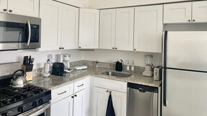 Eine moderne Küche mit weißen Schränken, Edelstahlgeräten, einer Arbeitsplatte aus Granit und einem Geschirrspüler.