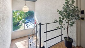 Eine Treppe mit Geländer, ein Blumentopf, eine Pendelleuchte und ein Blick auf einen Parkplatz durch ein Fenster.