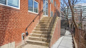 Ein Backsteinhaus mit einer Treppe, die zu einem Eingang im zweiten Stock führt, einem Bürgersteig und einem Fahrradständer.
