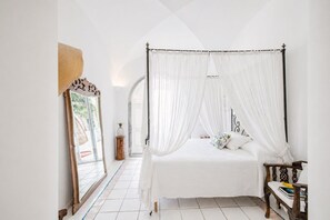 A bedroom with a four-poster bed, a large mirror, and a small wooden table. - Villa Monè by My Villa Collection (Capri)