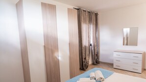 Un dormitorio con cama, cómoda, espejo y cortina.