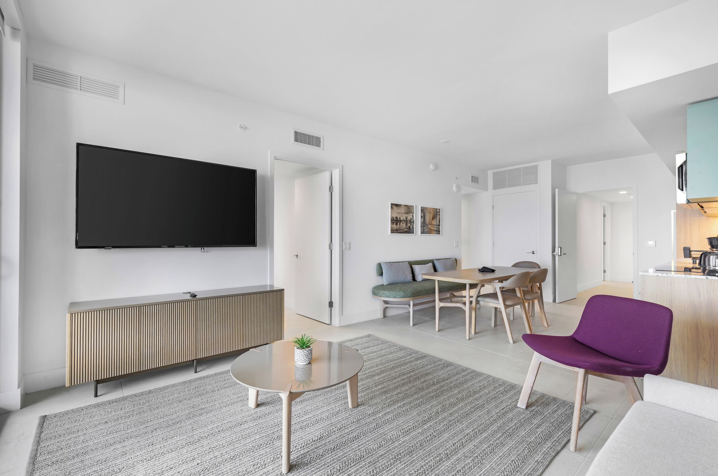 Una sala de estar moderna con televisor de pantalla plana, comedor y cocina.