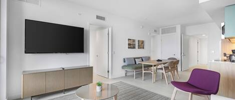 Una sala de estar moderna con televisor de pantalla plana, comedor y cocina.