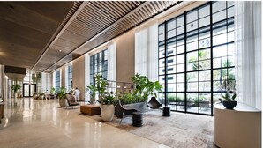 Um hall amplo com grandes janelas, mobiliário moderno e plantas em vasos.