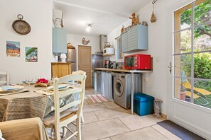 Eine Küche mit Waschmaschine, einer roten Mikrowelle und einem Essbereich mit Tisch für zwei Personen.