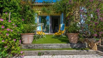 Un jardin avec une terrasse, deux chaises et une table.