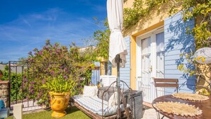 A garden with a metal bed, a large potted plant, and a dining table. - Bed and Breakfast 'Chez Sophie - Chambre Côté Mer' with Mountain View, Wi-Fi and Air Conditioning (Roquebrune-sur-Argens)