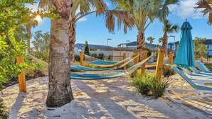 A sandy beach area with hammocks and lounge chairs, palm trees, and a clear sky. - NEW Mario World | Private Pool | Near Clubhouse (Davenport)
