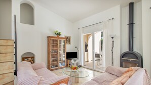 Een woonkamer met een bank, een glazen salontafel, een kast en een open haard.