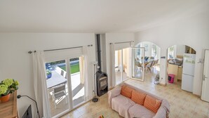 Een woonkamer met een bank, een open haard en uitzicht op het terras.