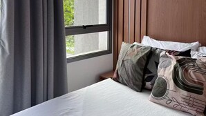 Une chambre d’hôtel dotée d’une grande fenêtre, d’un lit avec de nombreux oreillers et d’un mur recouvert de panneaux en bois.