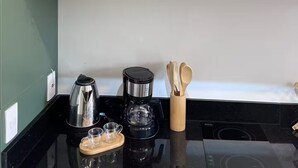 Une cuisine équipée d’une machine à café, d’un four à micro-ondes et d’une étagère où sont disposés des objets décoratifs.