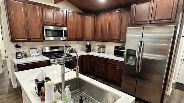 A modern kitchen with wooden cabinets, stainless steel appliances, and a marble island. - 3-bedroom cabin in amazing Running Springs with cozy vibes (Running Springs)