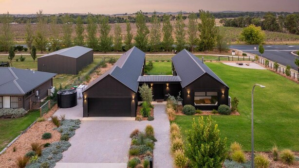 Ett modernt hus med ett stort garage, en välskött gräsmatta och utsikt över det omgivande landskapet.