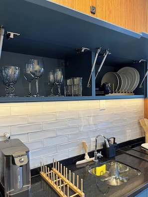 A kitchen with a blue backsplash, a stainless steel sink, and a dish rack. - Modern studio in Campo Belo, near Congonhas Airport. (São Paulo)