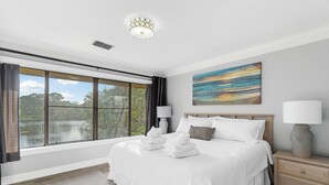 A bedroom with a large window, a bed with white linens, two bedside lamps, and a painting on the wall. - 3 Pools - PET FRIENDLY - Gulfside of Sandestin Resort (Miramar Beach)