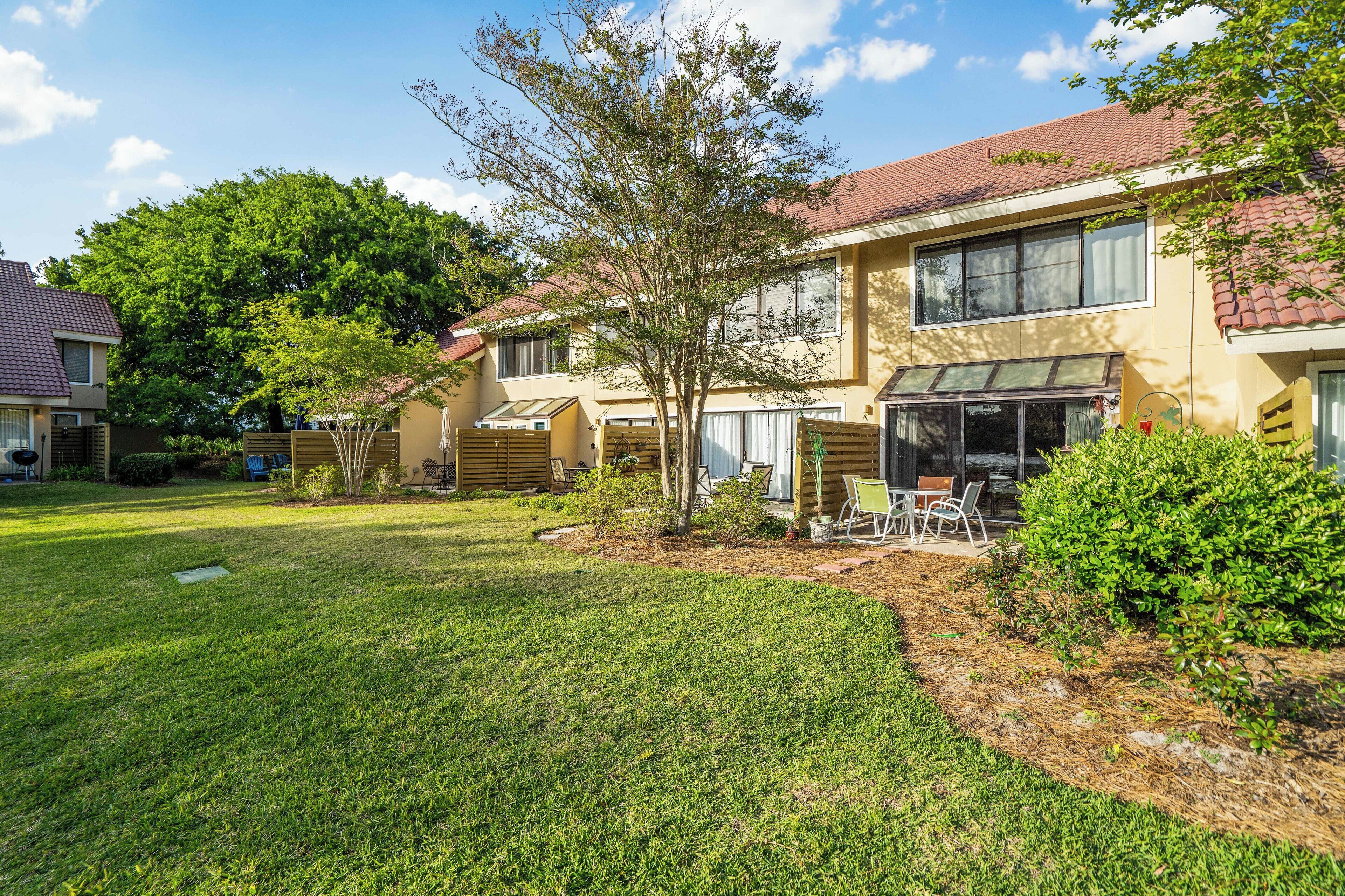 A residential building with a well-maintained lawn, a patio area, and a large tree.