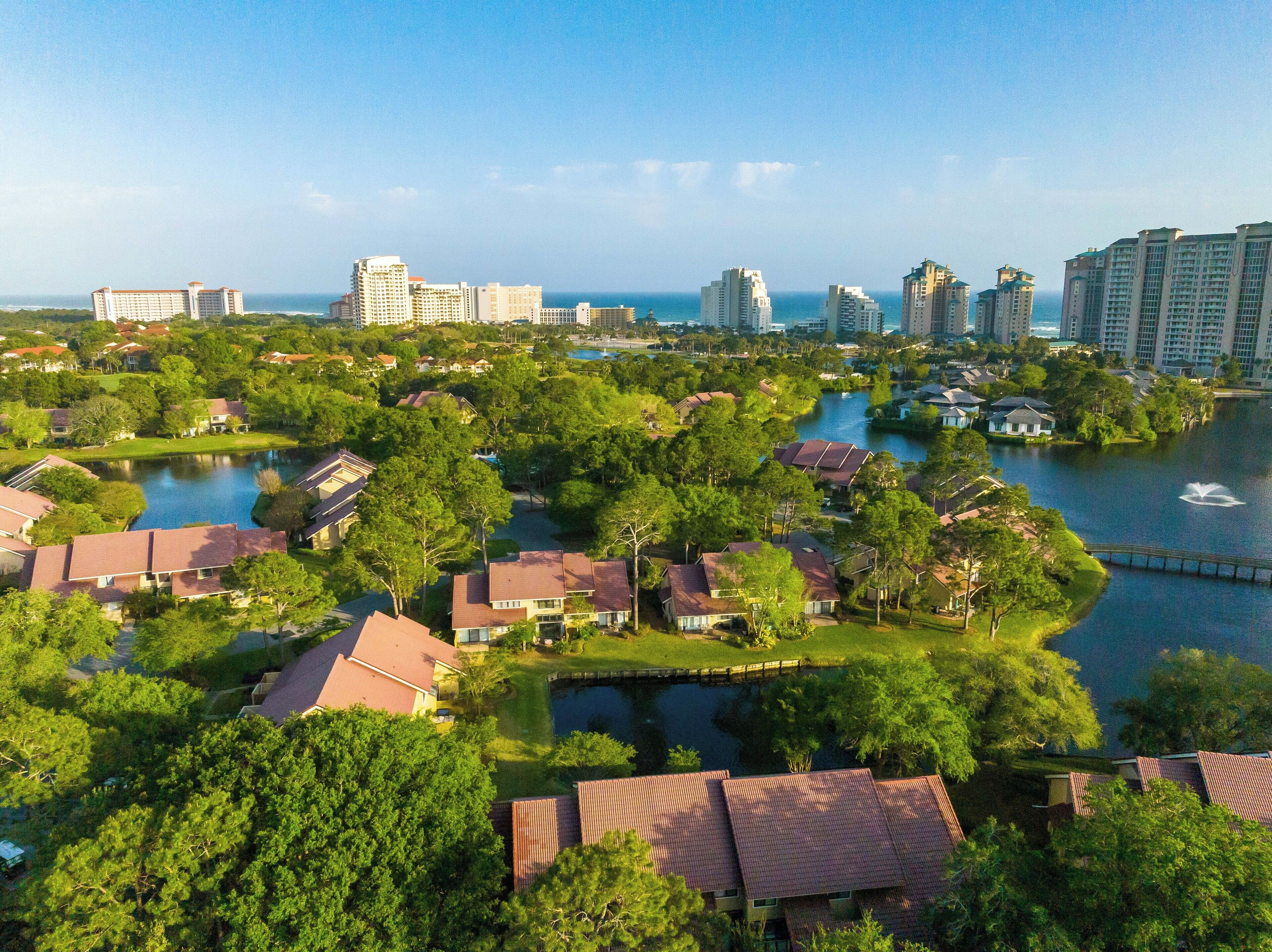 Un quartiere residenziale con case, un lago e sullo sfondo la silhouette di una città.