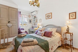 Un dormitorio con cama, cómoda, tocador y candelabro.