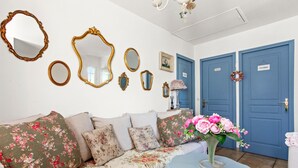 Una habitación con un sofá floral, una puerta azul y varios espejos en la pared.