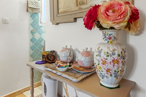 Uma bancada de cozinha com chá, um vaso com flores e um revestimento de azulejos decorativos.