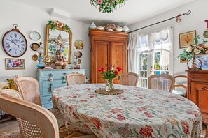 Una habitación con una mesa de comedor, sillas, un espejo y un gran armario de madera.