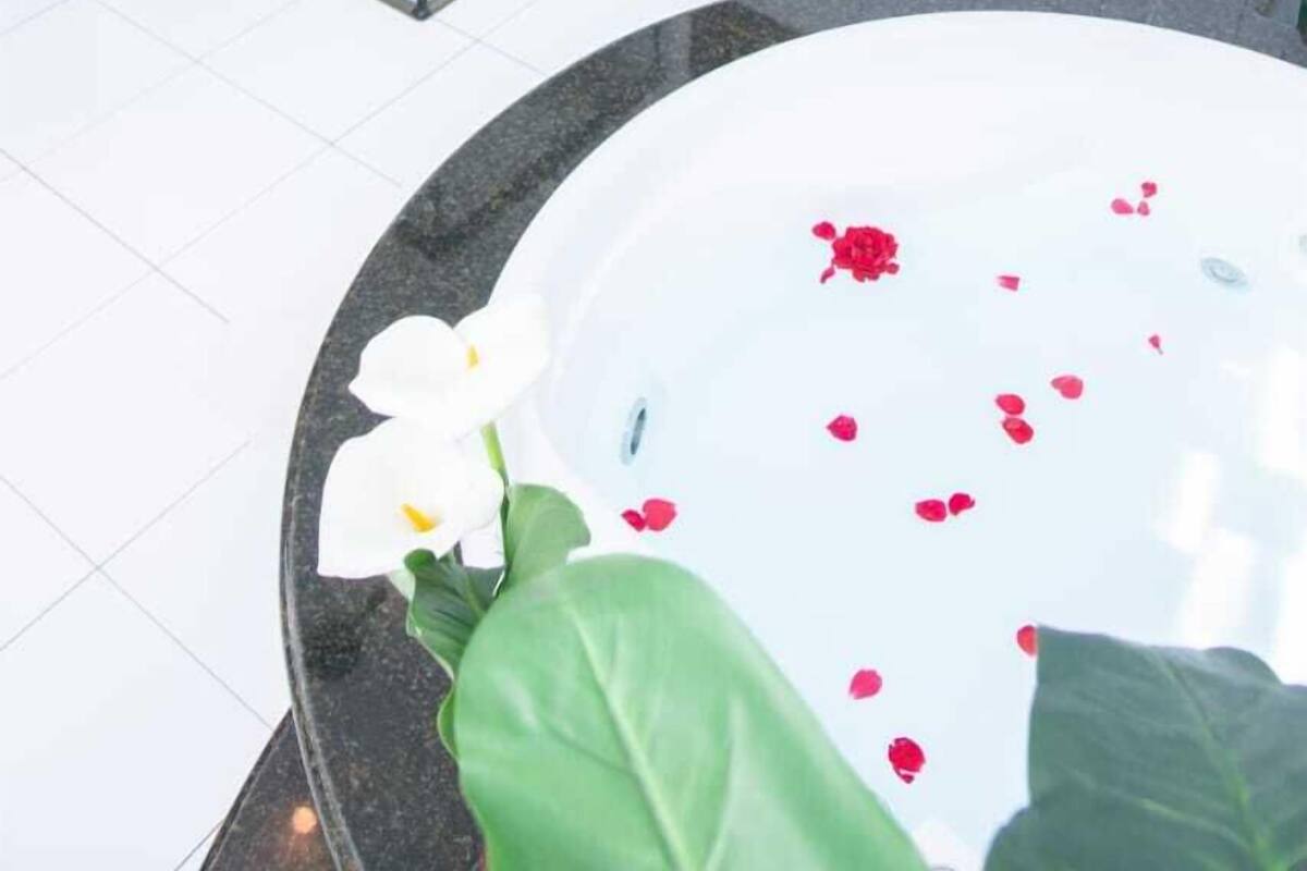 A bathroom with a glass shower enclosure, a white toilet, and a bathtub with rose petals.