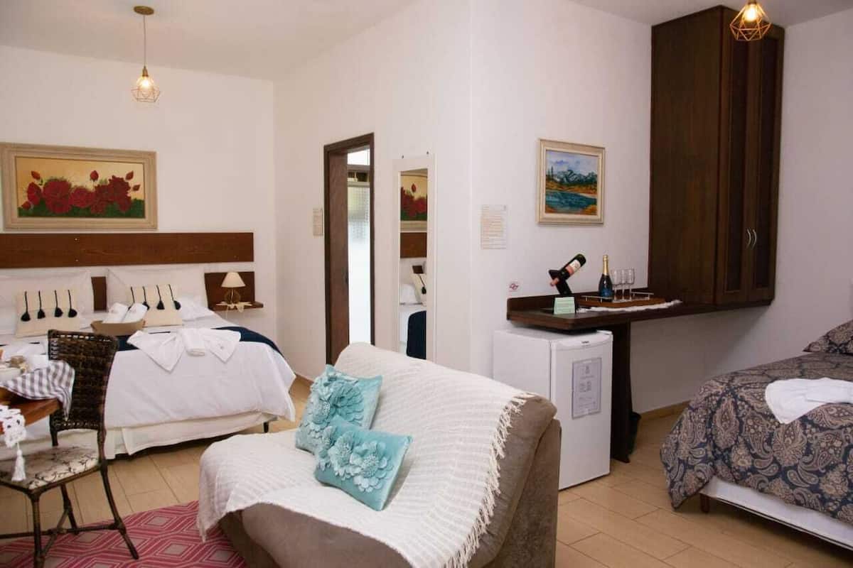 A hotel room with a bed, a desk, a chair, a small refrigerator, and a cabinet.
