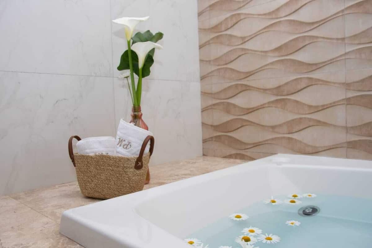 A bathroom with a bathtub, a woven basket with towels, and a wall with a wavy pattern.