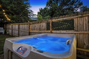 Ein Whirlpool mit Bedienfeld, umgeben von einem Holenzaun und Lichterketten.