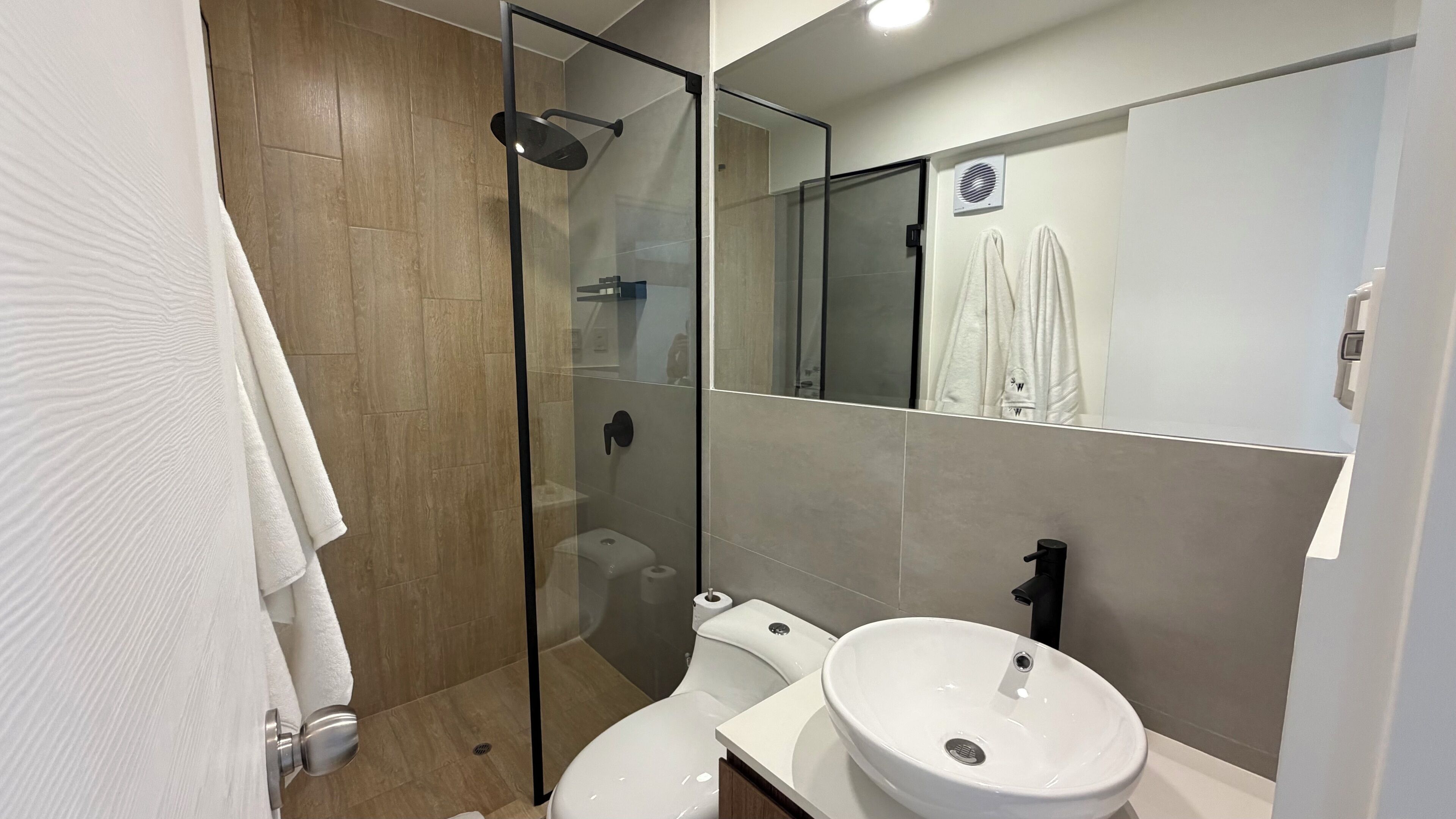 Une salle de bain moderne avec une douche à parois de verre, des toilettes et un lavabo.