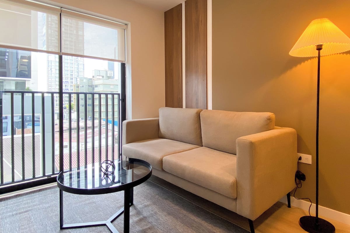 Un salon moderne avec un canapé, une table en verre et un lampadaire.