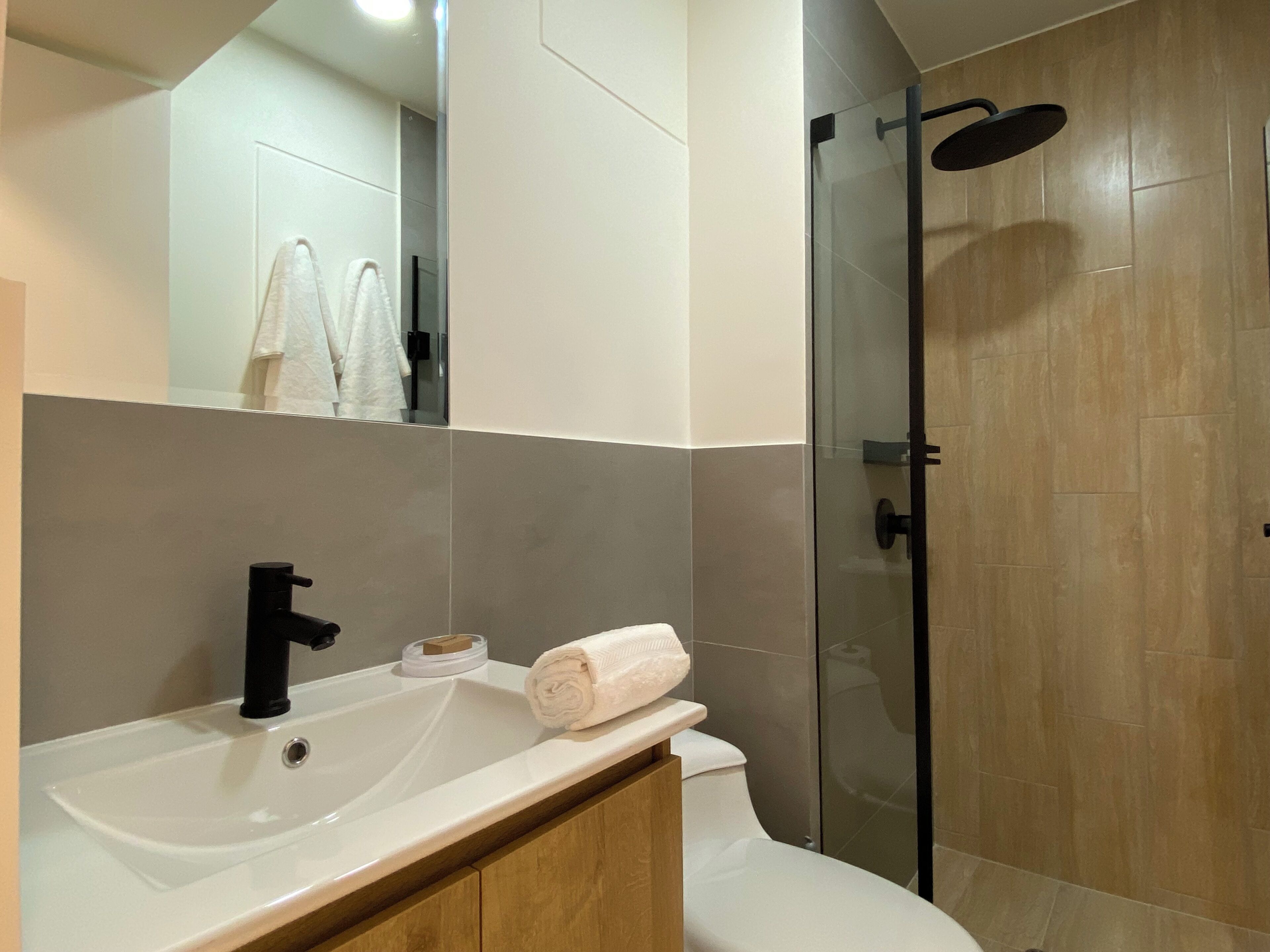 A modern bathroom with a white sink, black faucet, and a glass-enclosed shower.
