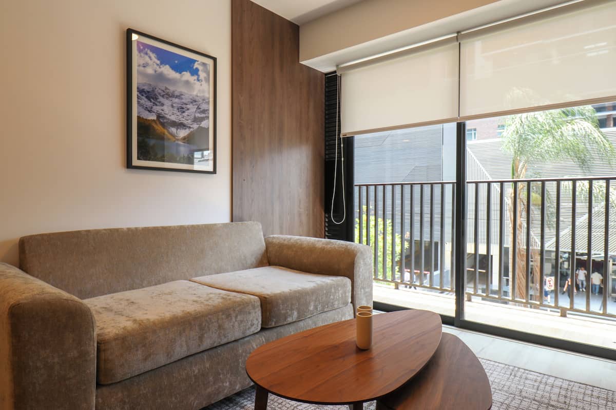 Un salon moderne avec un canapé, une table basse, un tableau encadré au mur et une grande fenêtre donnant sur l’extérieur.