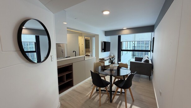 A modern interior with a dining area, kitchen, and living space, featuring a large window, a flat-screen TV, and a round mirror. - Amme by Wynwood House (Lima)